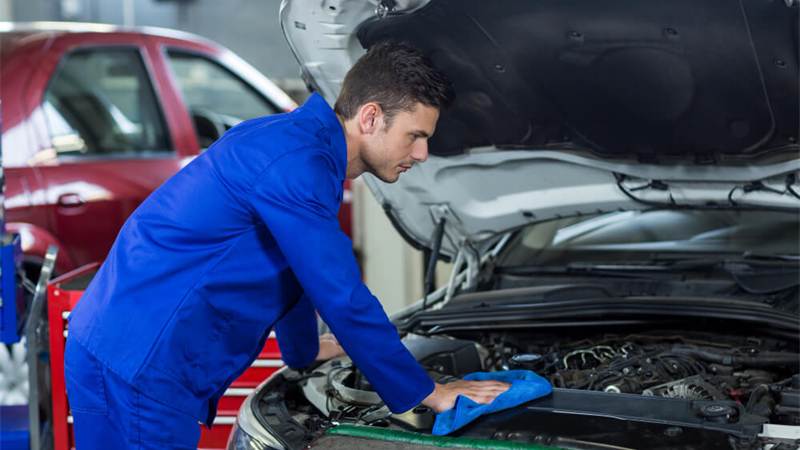Mechanic working under an open car hood